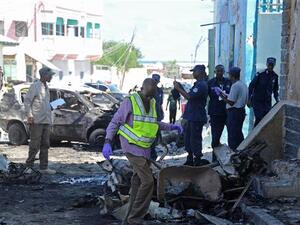Somali soldiers and investigators work at the site of an explosion outside a restaurant in Mogadishu on April 9, 2016 (AFP)