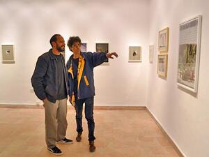 In this photo taken on Saturday, Mohammed Zakaria (left) and a viewer examine one of Zakaria’s photos at the Image Festival Amman (Photo by Yasmeen Kanaan)