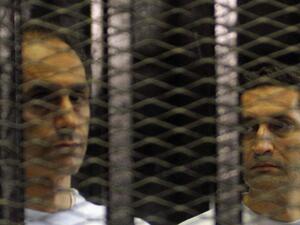 Alaa (R) and Gamal Mubarak, sons of ousted Egyptian president Hosni Mubarak, standing inside a cage in a courtroom during their verdict hearing in Cairo. (AFP/File)