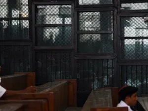 Egyptian Muslim Brotherhood defendants, including leader Mohamed Badie, stand behind bars during a trial in Cairo. (AFP/ File Photo)