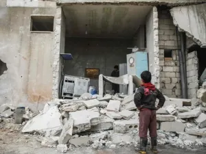 A Syrian boy looks at the fallen wall of a house which was damaged by an airstrike. (AFP Photo)