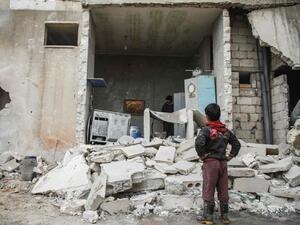 A Syrian boy looks at the fallen wall of a house which was damaged by an airstrike. (AFP Photo)