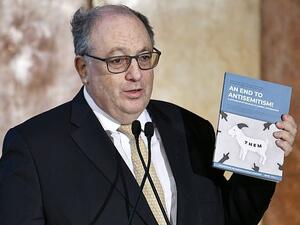 Ariel Muzicant, Vice-President of the European Jewish Congress, and co-author of the new document holds it up, showing the title 'An End to Antisemitism! A Catalogue of Policies to Combat Antisemitism' (AFP)