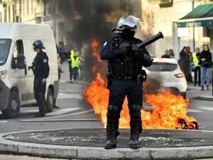 A French riot police officer stands next to a burning barricade during a demonstration against French government Education reforms on December 5, 2018 in Bordeaux, southwestern France. 
NICOLAS TUCAT / AFP
