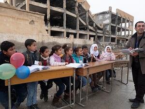 Haunted by the past: A bombed building used as an Isis prison is the backdrop to head Ibrahim Ismail’s talk with pupils (dailymail)