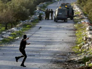 A Palestinian protester uses a sling to hurl stones towards Israeli troops (Twitter)