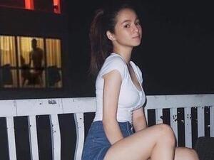 A young woman poses for a photo on a balcony. Nothing remarkable about that, until you spot what's going on in the background (Twitter)