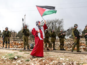 Palestinian woman walks with Palestinian flag (Shutterstock)	