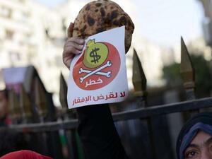 Egyptian protester holds bread along with a flyer in Arabic that reads 'Danger, no to loans that lead to poverty' during a rally in downtown Cairo on April 3, 2013. (AFP/Khaled Desouki) Egyptian protester holds bread along with a flyer in Arabic that reads 'Danger, no to loans that lead to poverty' during a rally in downtown Cairo on April 3, 2013. (AFP/Khaled Desouki)