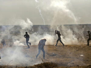 Palestinians take cover from tear gas smoke fired by Israeli force (AFP/File Photo)	