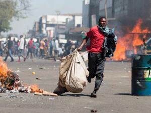 A street vendor flees with his goods as Zimbabwe opposition supporters clash with police in Harare. (AFP /Wilfred Kajese)