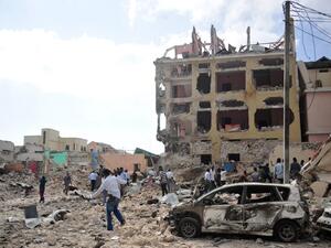 People react and walk among rubbles following an attack outside an hotel on January 25, 2017, in Mogadishu. At least seven people were killed after two car bombs exploded outside a popular Mogadishu hotel and gunmen forced their way inside the building and opened fire, police said. (AFP/Mohamed Abdiwahab)