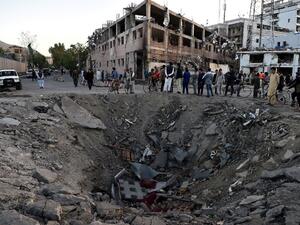 Afghan security forces and residents stand near the crater left by a truck bomb attack in Kabul on May 31, 2017. (AFP/Wakil Kohsar)