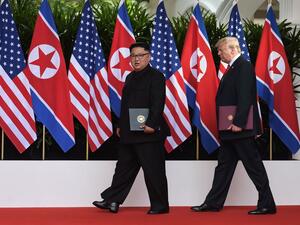 President Trump and North Korean leader Kim Jong Un carry their documents after the signing ceremony at the end of their summit. (AFP)