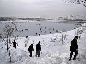 Afghan men climb up a snow covered hillside as youths play on the frozen surface of Qargha Lake on the outskirts of Kabul on February 10, 2017. (AFP/Wakil Kohsar)