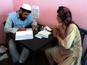 An Afghan man waits to receive his identification card to vote in upcoming elections. [AFP]