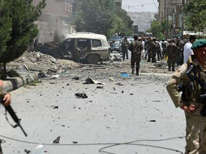 Security personnel and residents walk at the site of a car bomb blast that targeted the CARE International compound at Share Naw in Kabul. (AFP/Wakil Kohsar)