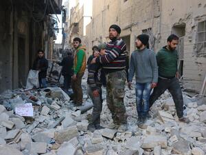 Civilians walk through the rubble of a neighborhood hit by airstrikes in Aleppo. (AFP/File)