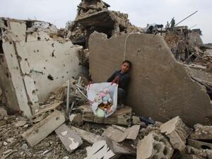 A Syrian boy sits with belongings he collected from the rubble of his house in Aleppo's Al-Arkoub neighborhood on December 17, 2016, after pro-government forces retook the area from rebel fighters. (AFP/Youssef Karwashan)