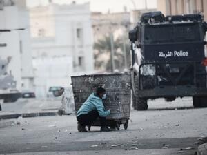 This file photo taken on January 2, 2015 shows a Bahraini protester taking cover behind a garbage container during clashes with riot police following a demonstration. (AFP/Mohamed al-Sheikh)