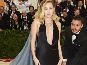 Miley Cyrus opted to go sans bra in a very plunging black gown by Stella McCartney that exposed not only some of her tattoos but generous glimpses of flesh. (Source: NEILSON BARNARD / GETTY IMAGES NORTH AMERICA / AFP)