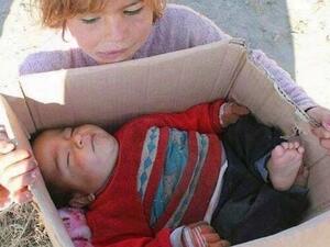 A little Syria refugee holds her baby brother who froze to death. (Arabsaga)