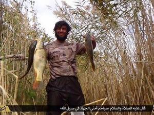 A Daesh militant shows off the fish he caught on a fishing trip. Note the U.S. Army logo on his shirt. (Twitter)