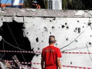 رجل ينظر إلى جدار تحطم جراء سقوط الصواريخ عليه من قطاع غزة في مدينة عسقلان بجنوب إسرائيل
