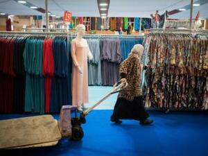 امرأة محجبة تمر من أمام ملابس للبيع خلال الاجتماع السنوي لمسلمي فرنسا شمال باريس 
