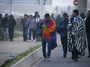 لاجئون يخملون أمتعتهم في ثاني أيام عملية نقلهم إلى سكن مؤقت في مراكز بفرنسا خلال أعمال هدم مخيم "الغابة" للمهاجرين في كاليه يوم الثلاثاء
