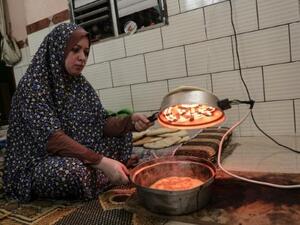 فلسطينية تعد الخبز مستفيدة من ساعات الكهرباء القليلة التي تصل المنازل يوميا في مخيم رفح للاجئين في غزة
