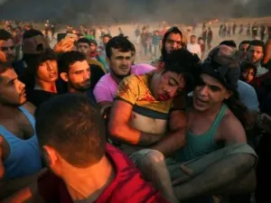 فلسطينيون يحملون فتى أصيب بجروح خلال مواجهات على السياج الفاصل بين إسرائيل وقطاع غزة

