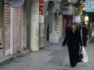 فلسطينية وسط محلات تجارية مغلقة بسبب الاضراب في غزة
