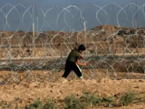 فتى فلسطيني يحاول قطع السياج الشائك عند الخط الفاصل بين قطاع غزة واسرائيل
