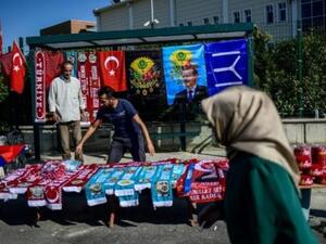 امرأة تسير أمام بسطة لبيع شالات تحمل صور الرئيس رجب طيب اردوغان قرب محكمة سجن سليفري في اسطنبول
