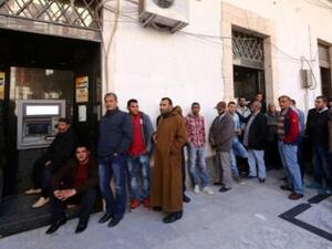 ليبيون ينتظرون بالدور لسحب أموال من جهاز صراف آلي أمام أحد المصارف في طرابلس 
