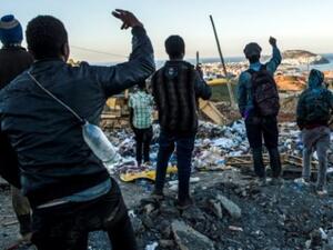 مهاجرون افارقة شبان ينظرون الى جيب سبتة بينما يقفون في مكب للنفايات في شمال المغرب 
