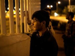 مهاجر افغاني ينظر الى عبارة عبر السياج في مرفأ باتراس (غرب اليونان)

