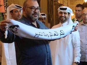 ملك المغرب يرفع وشاحا كتب عليه شعار "لكم العالم ولنا تميم"

