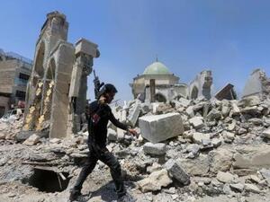 أحد أفراد قوة مكافحة الإرهاب في العراق يمشي بجوار أنقاض مسجد النوري الكبير في الحي القديم بمدينة الموصل في شمال العراق يوم الجمعة
