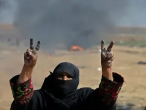 امرأة فلسطينية ترفع شارة النصر خلال احتجاجات على حدود قطاع غزة مع اسرائيل
