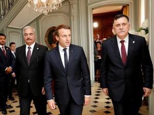 الرئيس الفرنسي إيمانويل ماكرون (في المنتصف) وإلى يساره حفتر وإلى يمينه السراج قرب باريس يوم الثلاثاء
