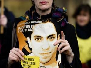 ناشطة من منظمة العفو الدولية تحمل صورة للمدون السعودي رائف بدوي خلال تظاهرة في برلين

