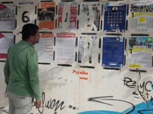 تونسي ينظر إلى ملصقات عليها قوائم المرشحين للانتخابات البلدية المرتقبة في القصرين بوسط تونس
