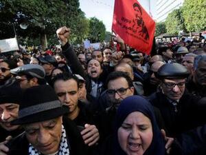 أشخاص يهتفون أثناء مظاهرات في الذكرى السابعة للإطاحة بالرئيس السابق زين العابدين بن علي في تونس يوم الأحد
