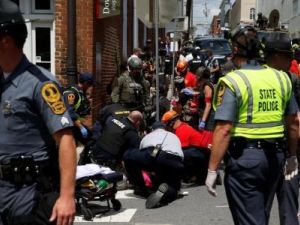 عمال إنقاذ يساعدون أناس أصيبوا بعد أن دهستهم مركبة في أحد شوارع مدينة تشارلوتسفيل بولاية فرجينيا الأمريكية يوم السبت

