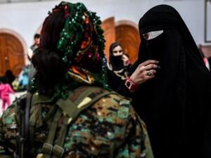 امرأة سورية تتحدث مع مقاتلة من قوات سوريا الديموقراطية فيما يتجمع المدنيون على الجانب الغربي اثر فرارهم من وسط الرقة

