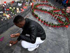 A man puts a candle near a peace symbol made with flowers on place de la Republique in Paris on November 13, 2016 as France marked the first anniversary of the Paris attacks for the relatives of the 130 people killed. (AFP/Alain Jocard)