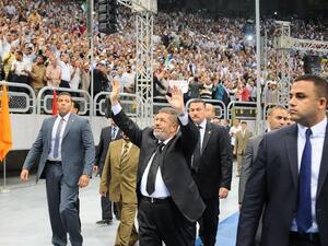 Egyptian President Mohammed Morsi (C) waves at thousands of Islamist supporters as he arrives for the "Support for Syria" rally at a Cairo stadium on June 15 (Egyptian Presidency / AFP)