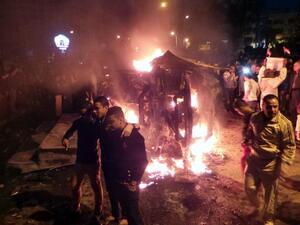 Angry Egyptians set fire to a microbus, said to be belong to a company owned by a businessman who supports the Muslim Brotherhood, after passengers allegedly held up four fingers, the symbol known as "Rabaa", during the funeral of those killed in a car bomb attack earlier in the day, in the Egyptian city of Mansoura, North of Cairo, on December 24, 2013. [AFP]